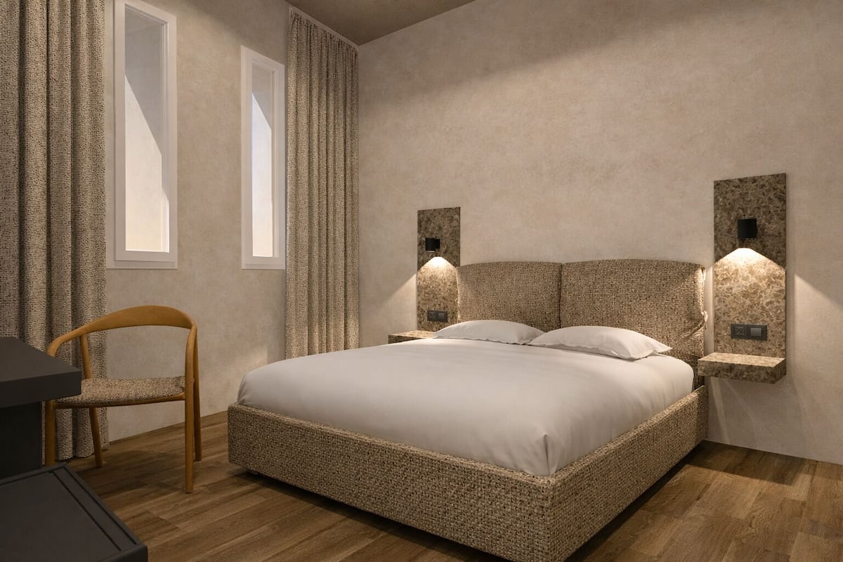 A bedroom with a large bed, a chair, and two wall-mounted lights.