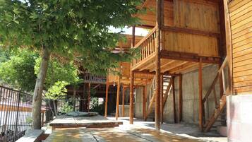 A wooden building with a balcony and a tree in front.