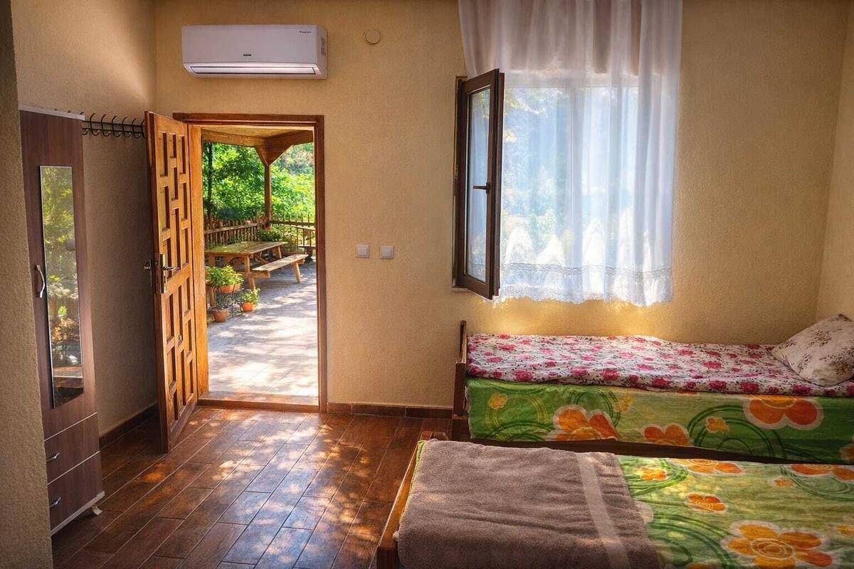 Un dormitorio con cama, ventana con vistas, puerta que da a un espacio exterior y un equipo de aire acondicionado.