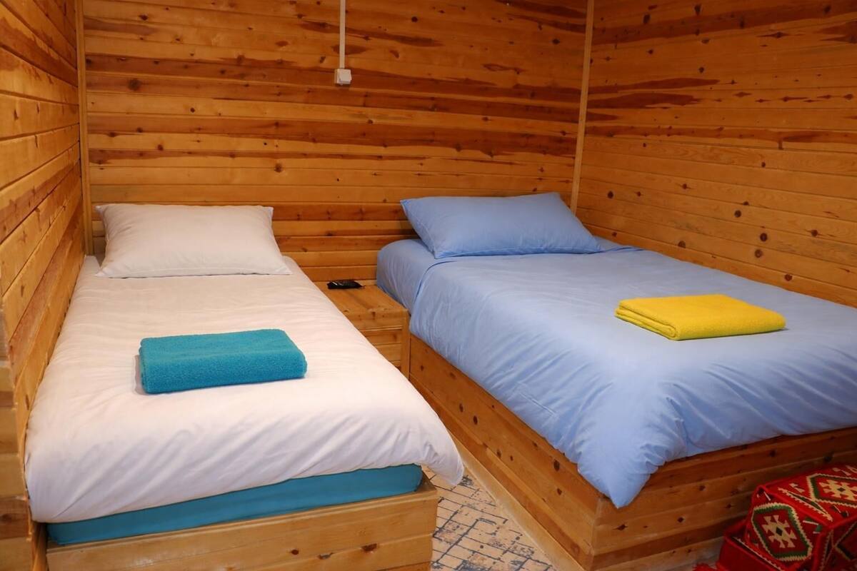 Una cabaña de madera con dos camas, cada una con almohada y manta.