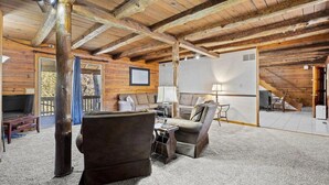 A rustic interior with exposed wooden beams, a sofa set, a small table, and a staircase leading to an upper level. - Lakefront Home w/ Private Apartment | Sleeps 12 | Boat Slip Available (Branson West)