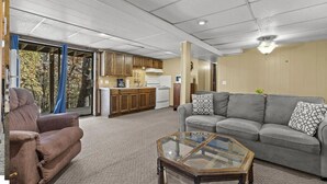 A living room with a sofa, armchair, and glass coffee table. - Lakefront Home w/ Private Apartment | Sleeps 12 | Boat Slip Available (Branson West)