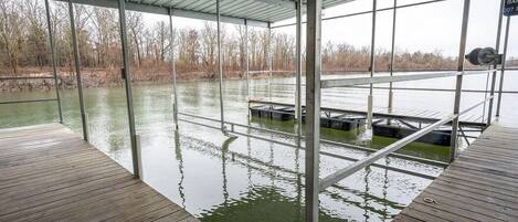 A covered dock area with a view of a water body and trees in the background.