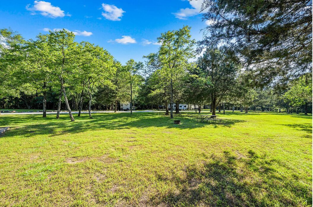 A park with trees, grass, and a picnic table.