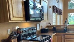 Una cocina con gabinetes de madera, microondas, estufa y lavamanos.