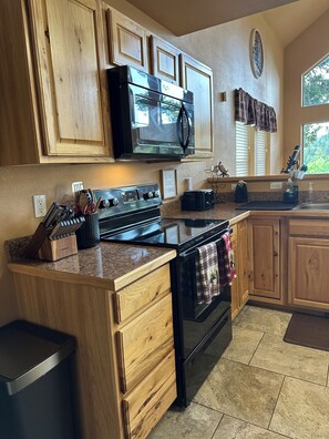 A kitchen with wooden cabinets, a microwave, stove, and a sink.