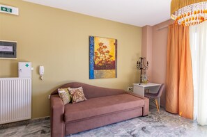 A room with a sofa, a painting, a desk with a chair, a radiator, and a chandelier. - Adorable 1-bedroom apartment with AC in charming Rethymno (Rethymno)