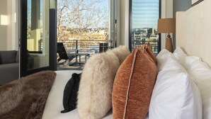 Ett hotellrum med en säng, en soffa, en lampa och utsikt genom en glasdörr.