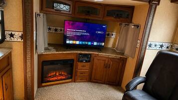 Ein Wohnzimmer mit Kamin, Fernseher und Ledersessel.