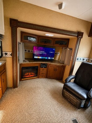 Ein Wohnzimmer mit Kamin, Fernseher und Ledersessel.