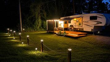 A RV with a covered outdoor area, a dining table, and chairs.