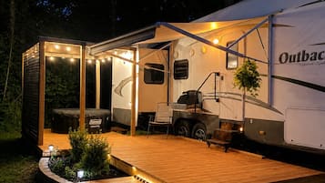 Ein Wohnmobil mit Überdachung, Holzterrasse und Sitzbereich im Freien.