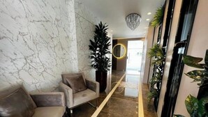Un vestíbulo con una pared de mármol, un sofá, una planta en maceta y un pasillo que conduce a una puerta.