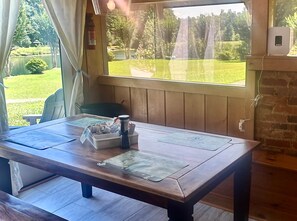 A wooden table with a view of a green landscape through a window. - Private 1940s Barn • Private Lake • Firepit (Saluda)