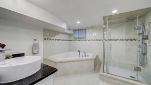 A modern bathroom with a large white bathtub, a glass-enclosed shower, and a round sink with a black countertop. - Bachelor apt.  Twenty minutes to BMO field. 
Close to Ossington and Dundas West. (Toronto)