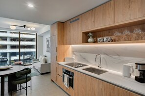 Une cuisine moderne avec des meubles en bois, un plan de travail en marbre, un four encastré et une machine à café.