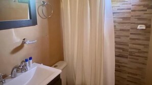 Un baño con inodoro, lavabo, espejo y cortina de ducha.