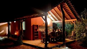 Un área de comedor al aire libre con un porche cubierto, una chimenea y una estructura de madera rústica.