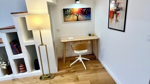 A modern room with a wooden desk, a chair, a lamp, and a painting on the wall. - Apartment Camille Pujol Toulouse (Toulouse)