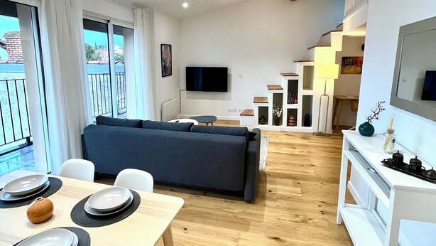 A modern living room with a sofa, dining table, and TV. - Apartment Camille Pujol Toulouse (Toulouse)