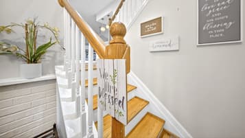 Una escalera con barandilla de madera, un cartel que dice 'We Are Blessed' y una pared con citas inspiradoras enmarcadas.
