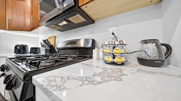 A kitchen with a gas stove, a microwave, wooden cabinets, and a coffee maker.