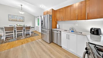 A modern kitchen with wooden cabinets, stainless steel appliances, and a dining area with a table and chairs.