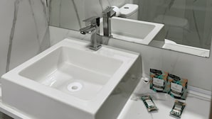 A bathroom with a white sink, a mirror, and marble walls. - Hotel Blox Sorriso (Sorriso)