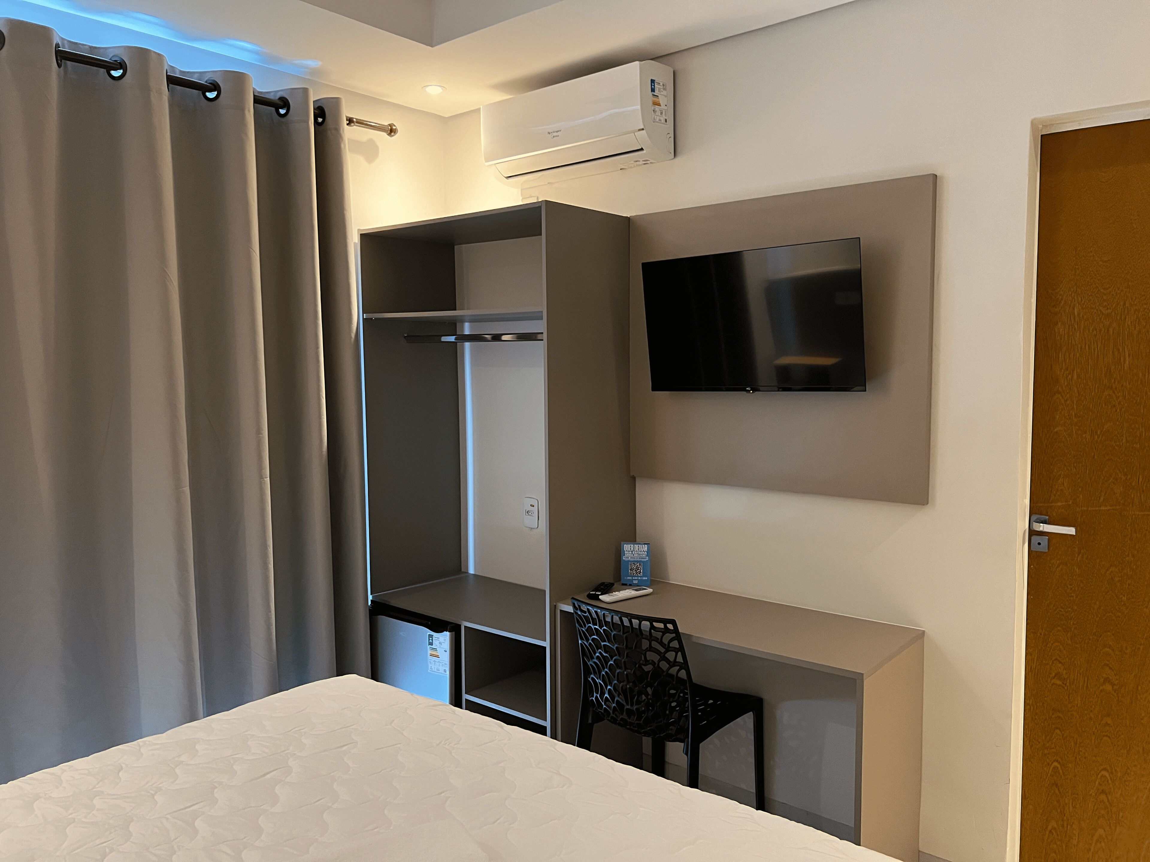 A hotel room with a bed, a desk, a TV, and a wardrobe.