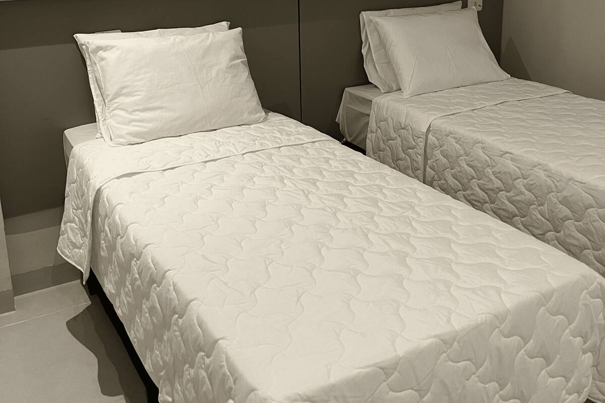 Two single beds with headboards, white bedding, and a plain wall.