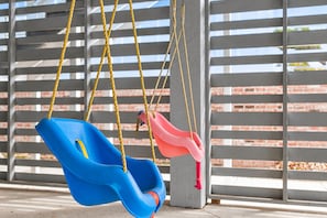 A swing set with two swings, one blue and one pink, suspended by ropes. - Gulf View Beach House / Sleeps 18 (Gulfport)