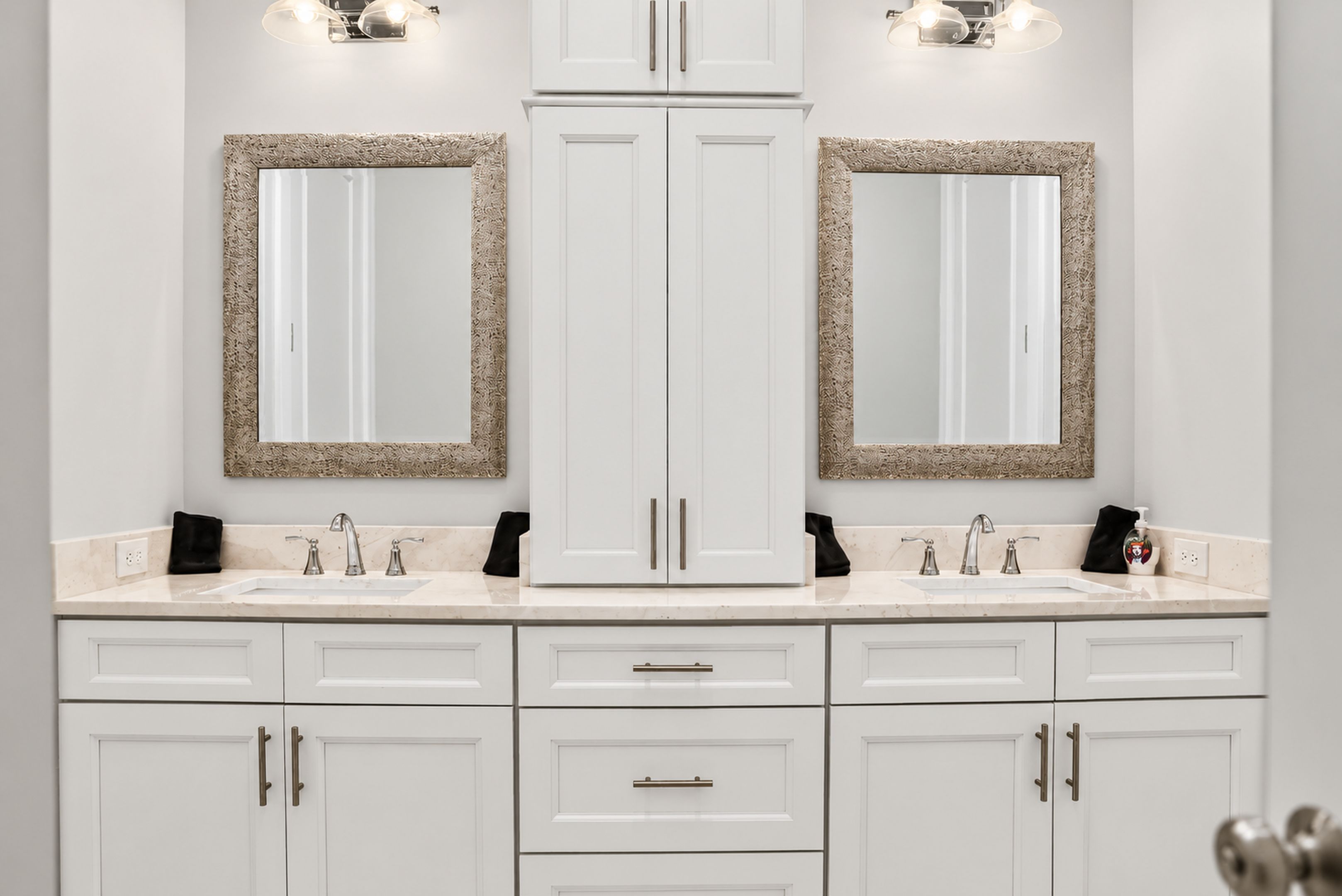 Un bagno con due lavandini, uno specchio e un armadietto.