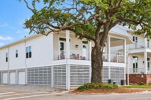 A two-story house with a covered porch and a large tree in front. - Gulf View Beach House / Sleeps 18 (Gulfport)