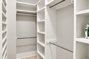 A white closet with multiple shelves and hanging rods, a towel on one of the shelves, and a hairdryer on the right side. - Gulf View Beach House / Sleeps 18 (Gulfport)