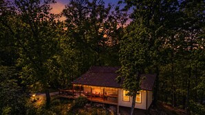 Eine Hütte mit Veranda, umgeben von Bäumen, im Abenddämmerung.