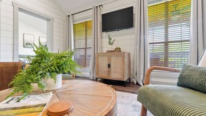 Ein Wohnzimmer mit einem runden Holztisch, einer Couch, einem Schrank und einem Fernseher an der Wand.
