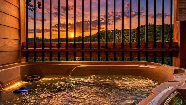 Ein Whirlpool mit Holumrandung, Blick auf einen Sonnenuntergang und ein Schild mit Text.