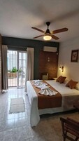 Una habitación de hotel con cama, ventilador de techo, equipo de aire acondicionado y vistas por una puerta de cristal.