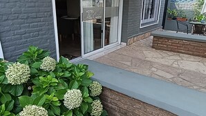 L’entrée d’un hôtel, avec un patio couvert, une enseigne bleue indiquant un centre d’accueil pour enfants, et une variété de plantes.
