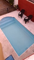 Una piscina rectangular con revestimiento azul, rodeada por una solana de hormigón.
