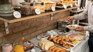 Un buffet de petit-déjeuner proposant une variété d'aliments, notamment des fruits, des céréales et des viennoiseries, le tout clairement étiqueté.