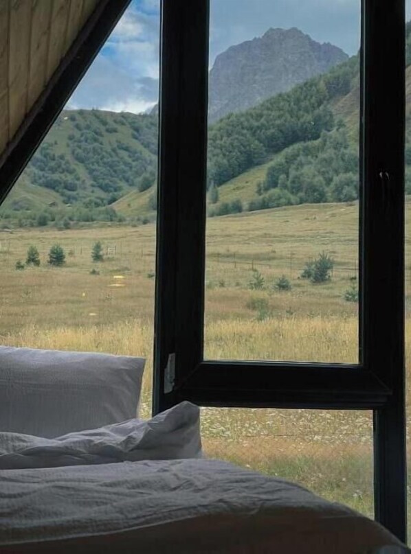 Una habitación con un amplio ventanal que ofrece vistas a un paisaje montañoso.