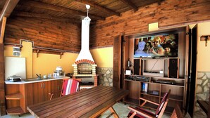 Un intérieur en bois avec une cheminée en pierre, une table en bois et un téléviseur.