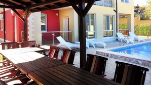 Un espace extérieur avec une piscine, des chaises longues et une table en bois.
