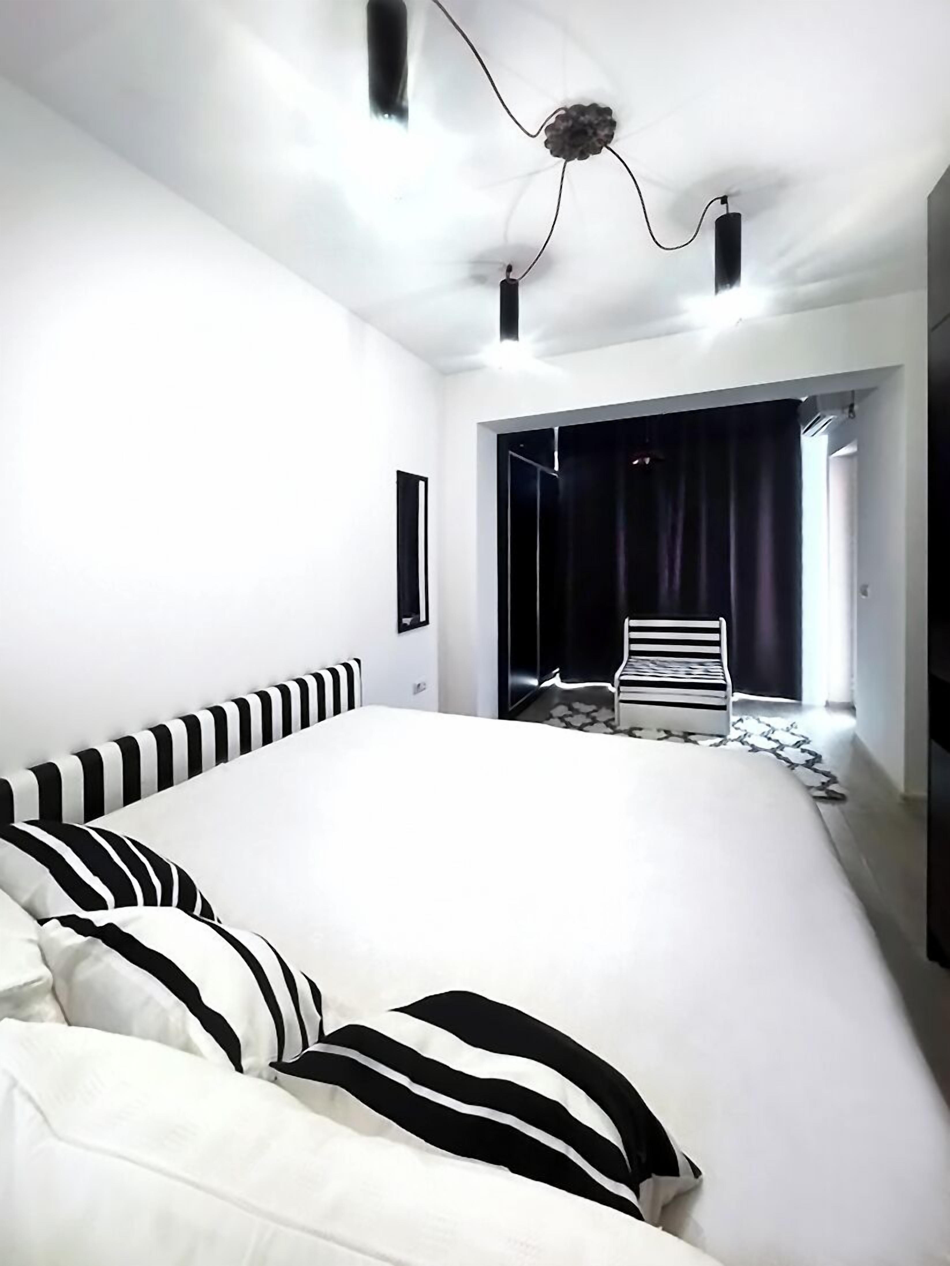A modern bedroom with a large bed, a chair, and a view of the outside.