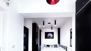 Une chambre à coucher moderne avec un lit, un élément décoratif rouge, une armoire noire et une suspension.