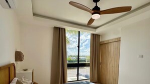 Ein Hotelzimmer mit Bett, Deckenventilator, einem Fenster mit Vorhängen und Blick ins Freie.