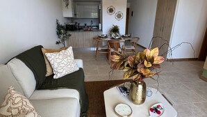 Ein Wohnzimmer mit einer Couch, einem Couchtisch und einem Essbereich im Hintergrund.