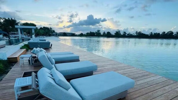 Eine Holzterrasse mit Liegestühlen und einem Pool.