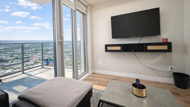 Un salon moderne avec une grande fenêtre, un téléviseur à écran plat et une petite table.